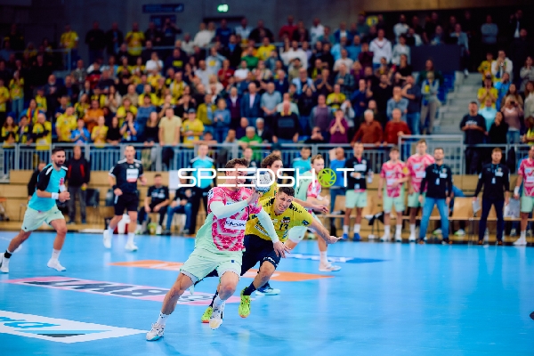 Ein Spieler von Rhein Neckar Löwen greift mit dem Ball im Angriff an, während ein Spieler von Füchse Berlin verteidigt.