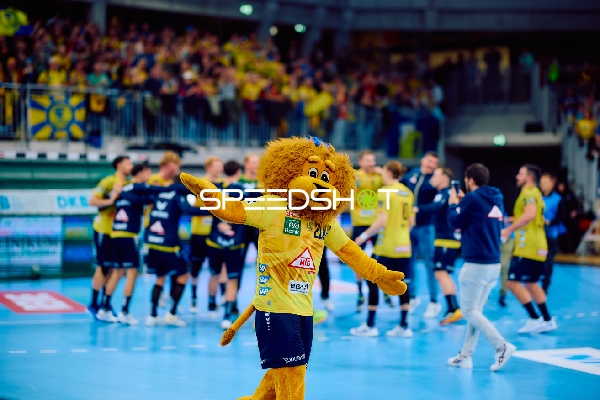 Ein Maskottchen auf dem Spielfeld feiert mit den Fans im Hintergrund.