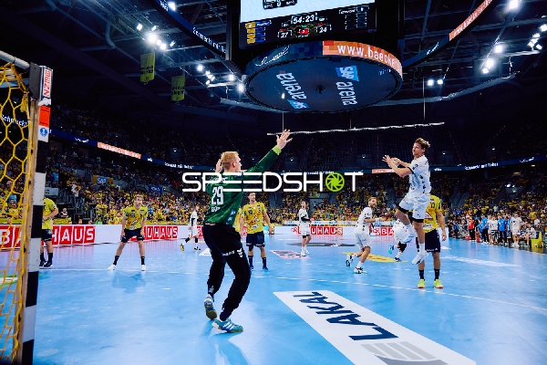 Ein Spieler von THW Kiel springt zum Wurf, während der Torwart von Rhein Neckar Löwen bereit ist, den Ball abzuwehren.