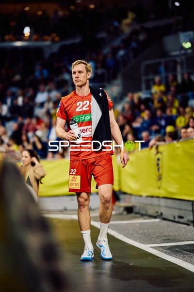 Spieler im roten Auswärtstrikot geht an der Seitenlinie entlang.