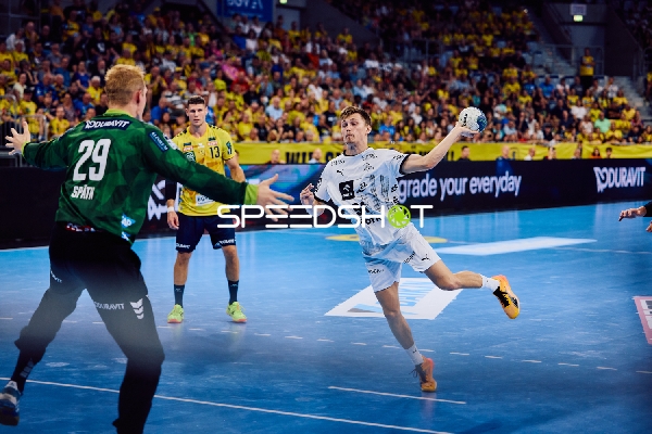 Ein Spieler von THW Kiel springt zum Wurf, während der Torwart von Rhein Neckar Löwen bereit ist, zu verteidigen.