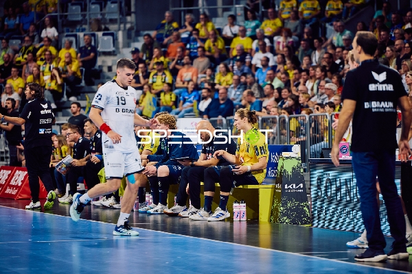 Ein Spieler von MT Melsungen mit der Nummer 19 bewegt sich entlang der Seitenlinie.