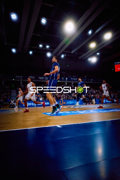 Spieler in Bewegung auf dem Spielfeld während eines Basketballspiels.