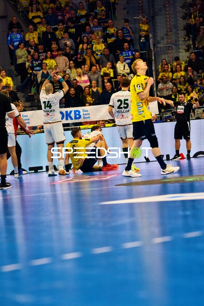 Ein Spieler der Rhein Neckar Löwen liegt während des Spiels am Boden, während andere Spieler verwickelt sind.