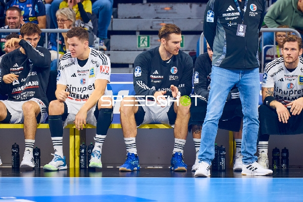 Spieler von THW Kiel sitzen auf der Auswechselbank und beobachten das Spielgeschehen.