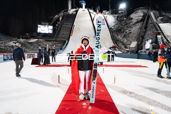 Athletin mit Flagge vor Skisprungschanze