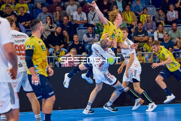 Ein Spieler der Rhein Neckar Löwen mit der Nummer 23 springt kraftvoll zum Torwurf, während er von einem Gegenspieler mit der Nummer 7 des HC Erlangen verteidigt wird.