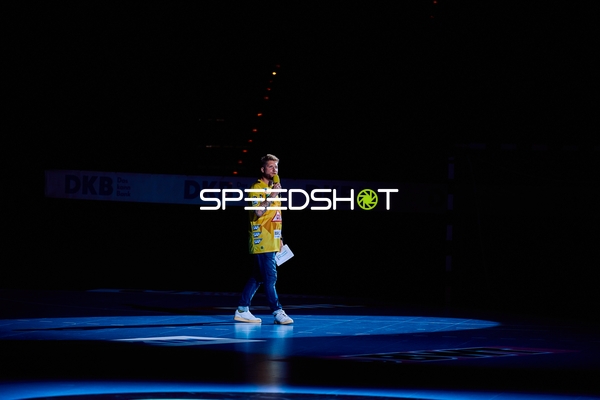 Ein Moderator steht im Rampenlicht auf dem Spielfeld.