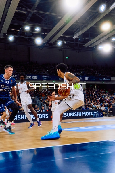 Ein Spieler von Brose Bamberg dribbelt den Ball, während MLP Academics Spieler verteidigen.