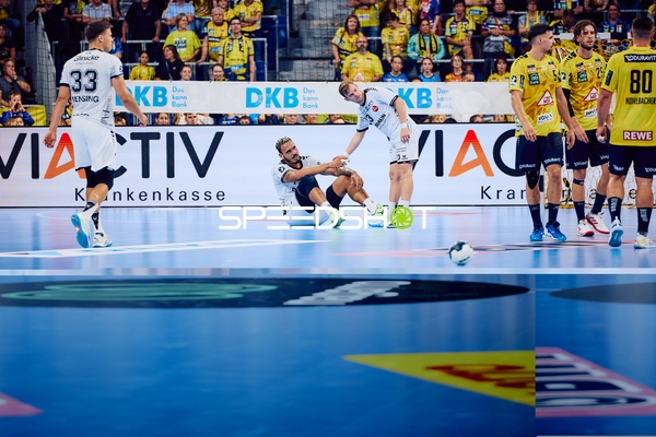 Ein Spieler von MT Melsungen sitzt auf dem Boden, während ein anderer ihm aufhilft. Spieler von Rhein Neckar Löwen stehen daneben.