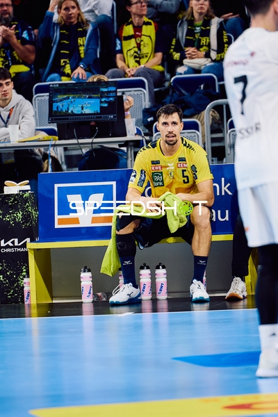 Ein Spieler der Rhein Neckar Löwen mit der Nummer 5 sitzt auf der Bank und beobachtet das Spiel.