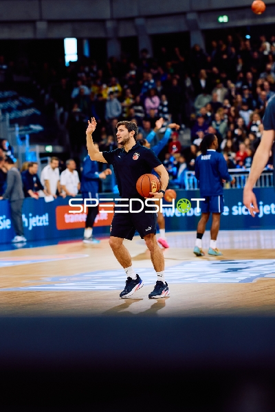 Ein Spieler von Brose Bamberg wärmt sich mit einem Ball auf dem Spielfeld auf.