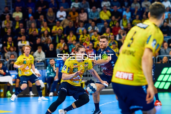 Ein Spieler der Rhein Neckar Löwen dribbelt den Ball, während ein Spieler der SG Flensburg Handewitt in die Verteidigung geht.