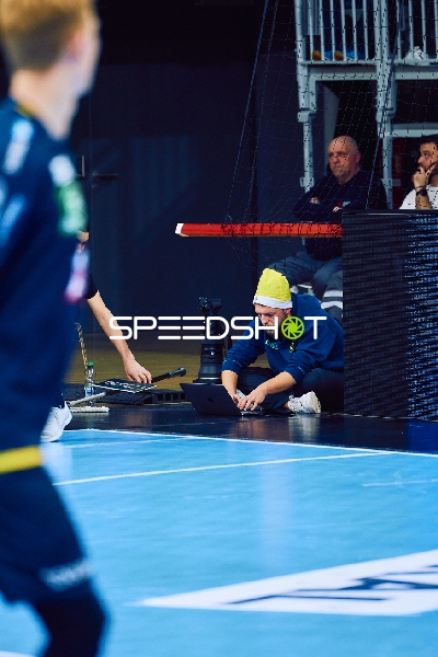 Ein Techniker arbeitet am Spielfeldrand, während ein Spieler vorbeiläuft.