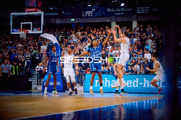Ein Spieler von Brose Bamberg versucht einen Wurf, während Spieler der MLP Academics Heidelberg verteidigen.