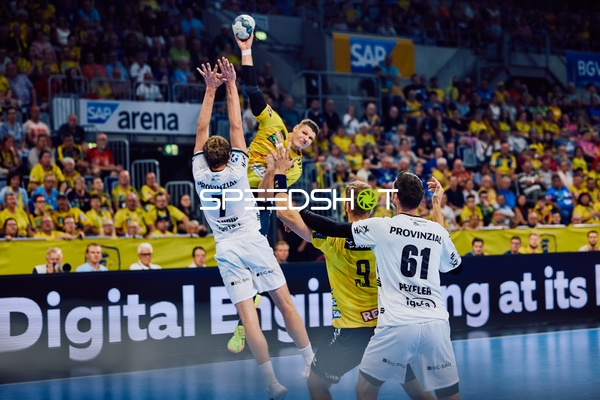 Ein Spieler der Rhein Neckar Löwen springt, um den Ball zu werfen, während zwei Spieler von THW Kiel versuchen, in der Abwehr zu blocken.