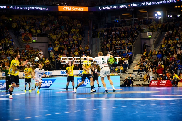 Ein Spieler von Rhein Neckar Löwen wirft den Ball in Richtung Tor, während ein Spieler von HSG Wetzlar versucht zu blocken.