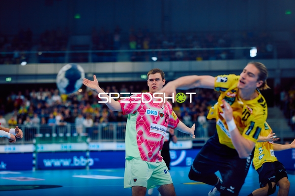 Juri Knorr von den Rhein Neckar Löwen wirft den Ball in einem Angriffsspielzug, während Max Beneke von den Füchsen Berlin verteidigt.