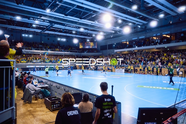 Ein Handballspiel findet in einem vollbesetzten Stadion statt.