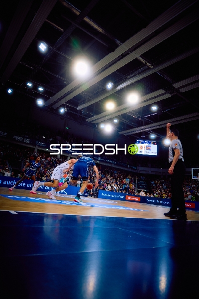 Ein Spieler versucht, an einem Gegenspieler vorbeizudribbeln, während der Schiedsrichter eine Entscheidung anzeigt.