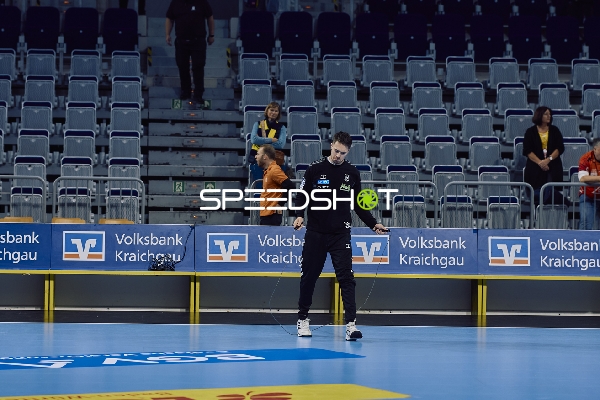 Ein Trainer bereitet das Spielfeld für ein Handballspiel vor.