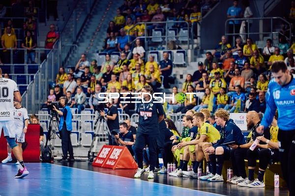 Spieler auf der Bank und Trainer in Aktion