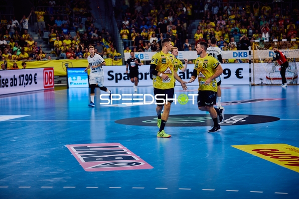 Zwei Spieler der Rhein Neckar Löwen feiern auf dem Spielfeld.