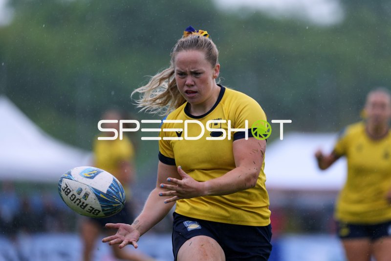 Rugby-Spielerin im Ballkontakt bei Regenmatch in Hamburg