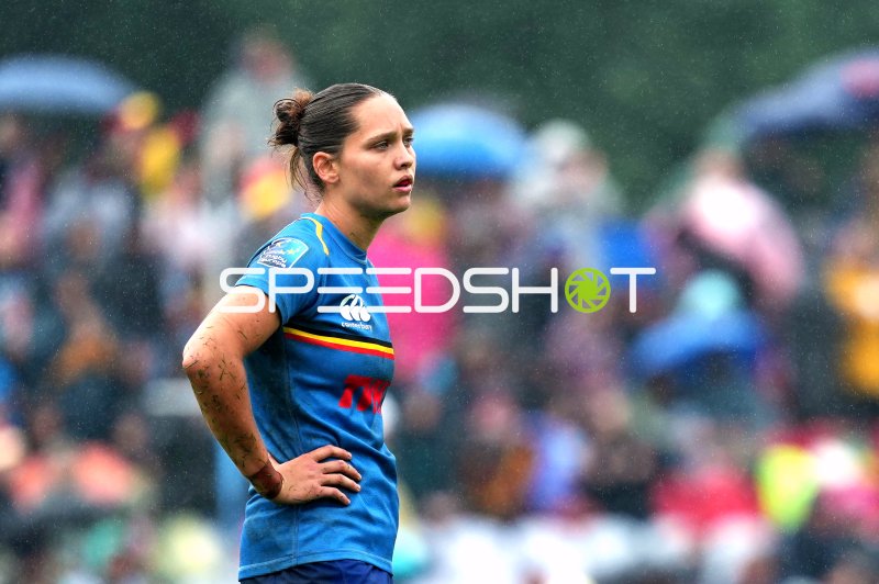 Rugby-Spielerin im blauen Trikot mit Rugby Europe-Logo im Regen