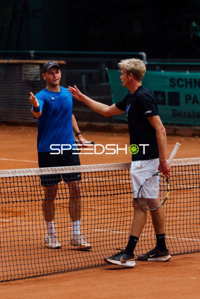 Zwei Tennisspieler im Gespräch am Netz auf dem Sandplatz