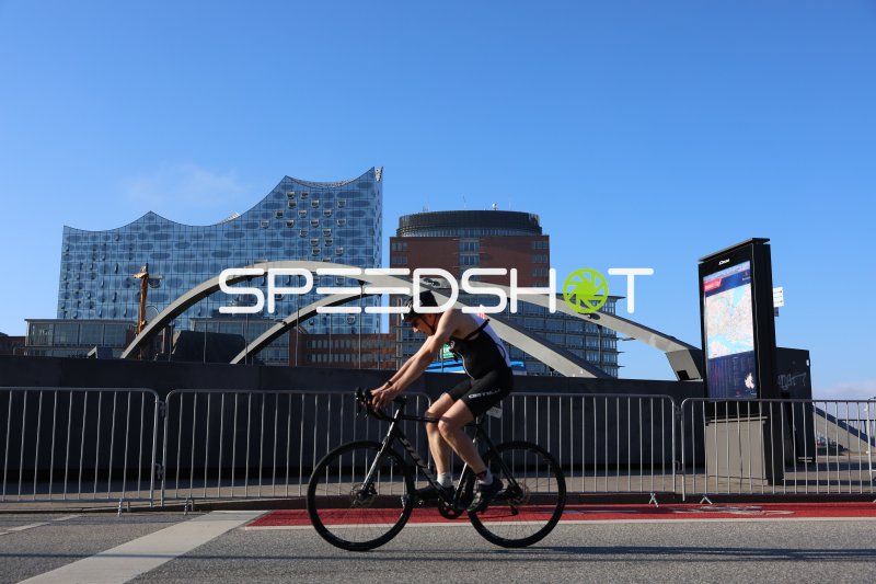 Triathlet auf dem Rad vor der Elbphilharmonie in Hamburg
