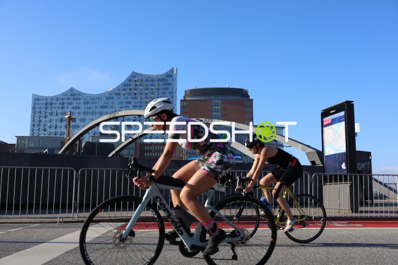 Zwei Triathletinnen auf der Radstrecke vor der Elbphilharmonie in Hamburg