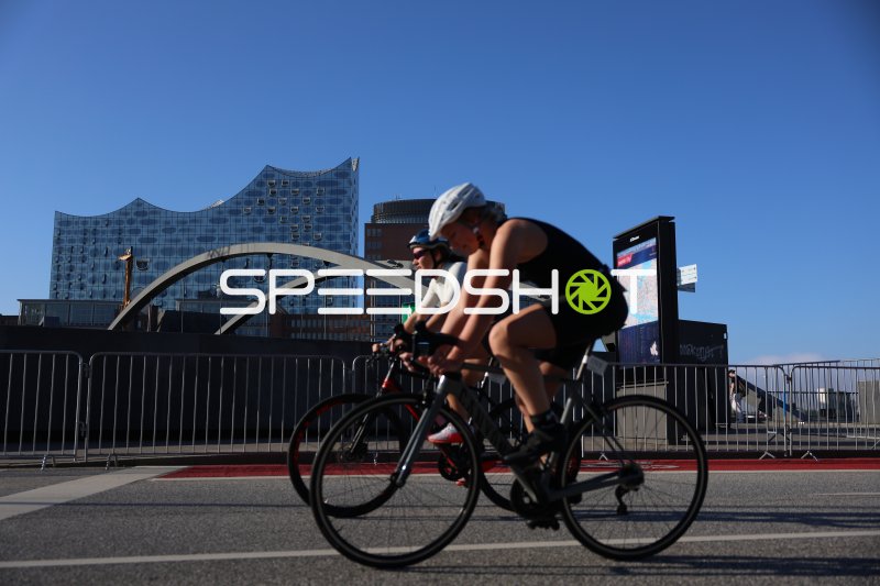 Zwei Triathleten auf der Radstrecke vor der Elbphilharmonie in Hamburg