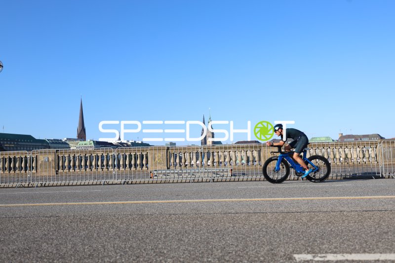 Triathlet auf dem Rad am Jungfernstieg mit Hamburger Skyline