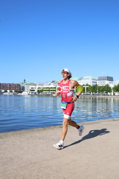 Triathlet in rotem Rennanzug beim Laufen an der Binnenalster, Hamburg