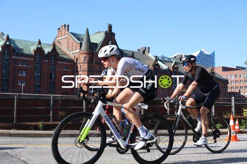 Triathleten auf der Radstrecke, im Hintergrund. Die Speicherbauten und die Elphi