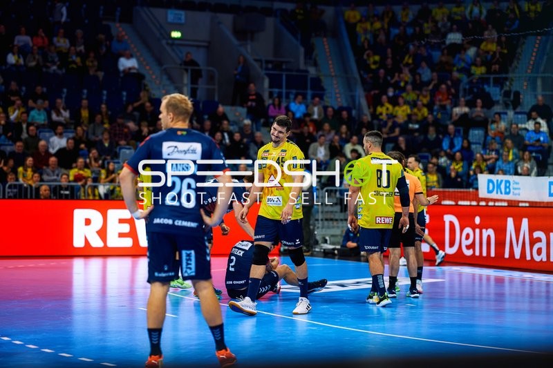 Ein Spieler von Rhein Neckar Löwen interagiert mit einem am Boden liegenden Gegenspieler.