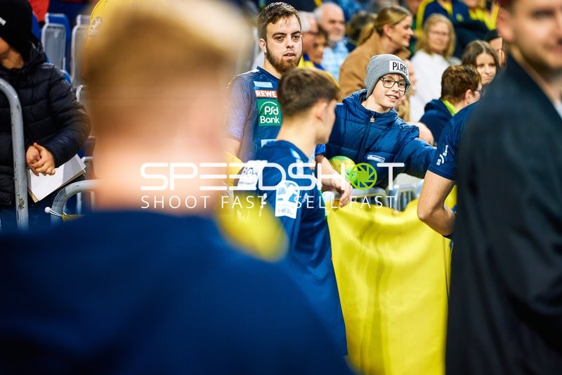 Spieler von SG Flensburg Handewitt interagieren mit den Fans am Spielfeldrand.