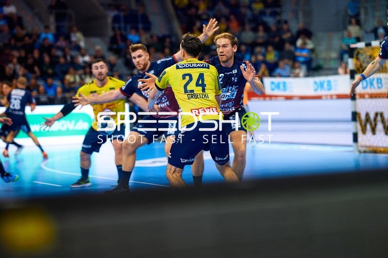 Ein Spieler von Rhein Neckar Löwen setzt zu einem Wurf an, während mehrere Abwehrspieler von SG Flensburg Handewitt versuchen zu blocken.