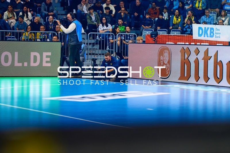 Das Bild zeigt das Spielfeld mit Kameraleuten und Zuschauern im Hintergrund, keine Spieler in Aktion.