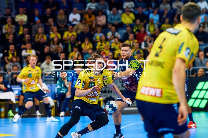 Ein Spieler der Rhein Neckar Löwen dribbelt den Ball, während ein Spieler der SG Flensburg Handewitt in die Verteidigung geht.