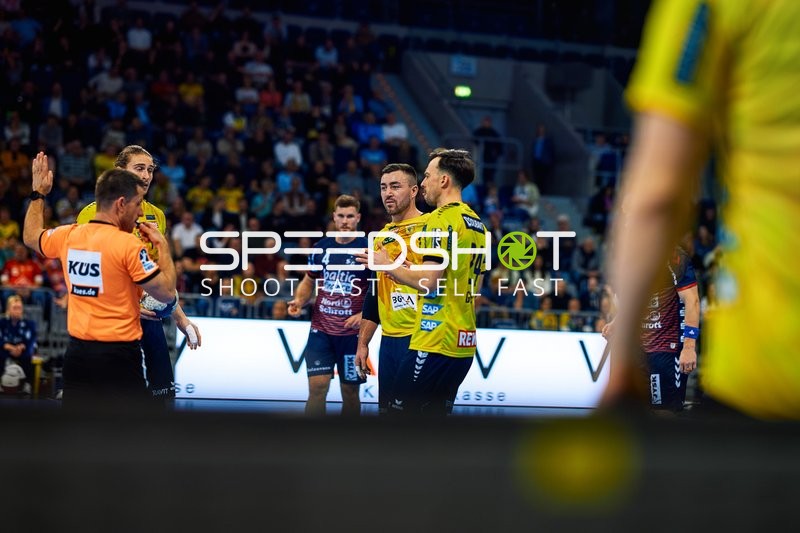 Spieler von Rhein Neckar Löwen diskutieren mit einem Spieler der SG Flensburg Handewitt.