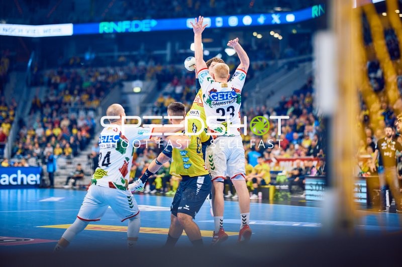 Spielszene mit zwei Abwehrspielern des SC Magdeburg, die einen Angriffsspieler der Rhein Neckar Löwen blockieren.