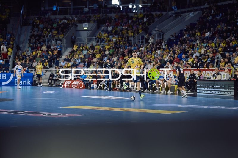 Ein Spieler der Rhein Neckar Löwen bewegt sich mit dem Ball vor der Bank.