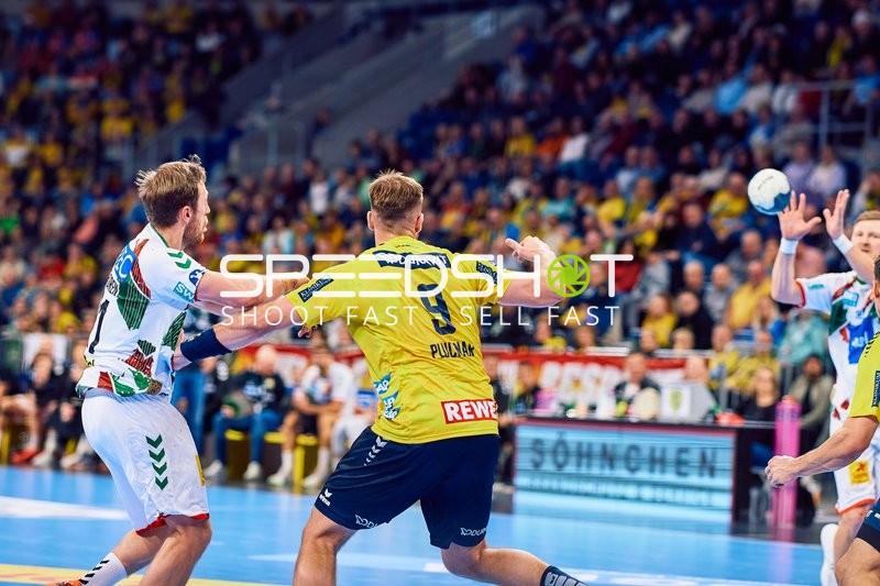 Ein Spieler der Rhein Neckar Löwen versucht, einen Wurf gegen die Verteidigung des SC Magdeburg zu machen.