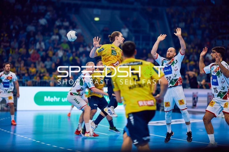 Ein Spieler der Rhein Neckar Löwen versucht einen Wurf, während mehrere Spieler von SC Magdeburg verteidigen.