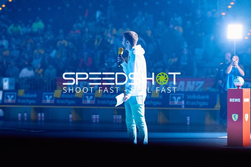 Moderator spricht mit einem Mikrofon in der Arena.