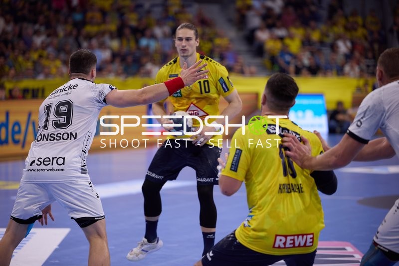 Ein Spieler von Rhein Neckar Löwen bereitet sich darauf vor, den Ball zu passen, während er von einem Spieler von SC Magdeburg verteidigt wird.