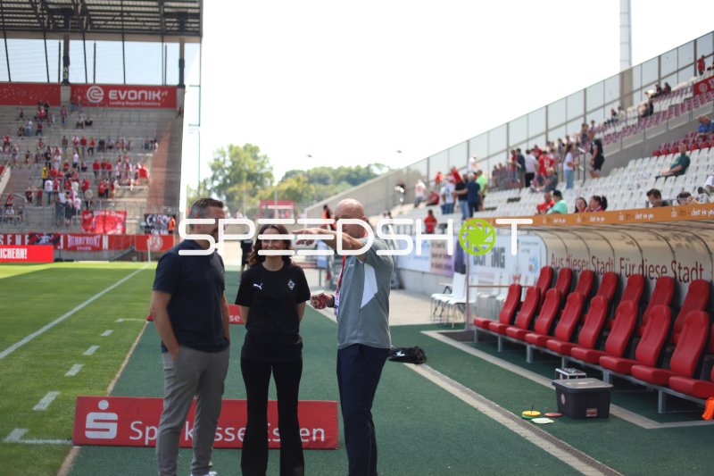 Drei Personen im Gespräch an der Seitenlinie im Stadion an der Hafenstraße