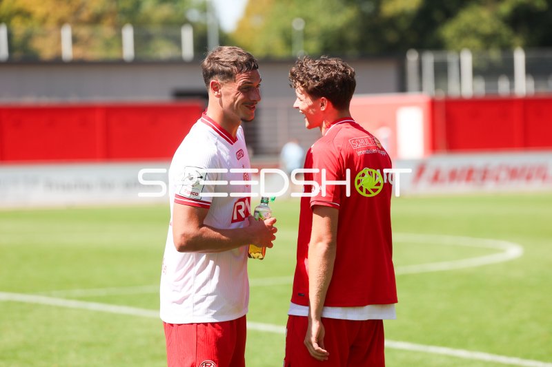 Zwei Rot-Weiss Essen Spieler im Gespräch am Spielfeldrand